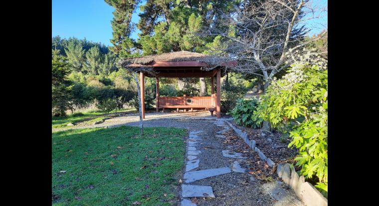 A shelter with seating, gravel and varied terrain, stone work poses trip hazard.